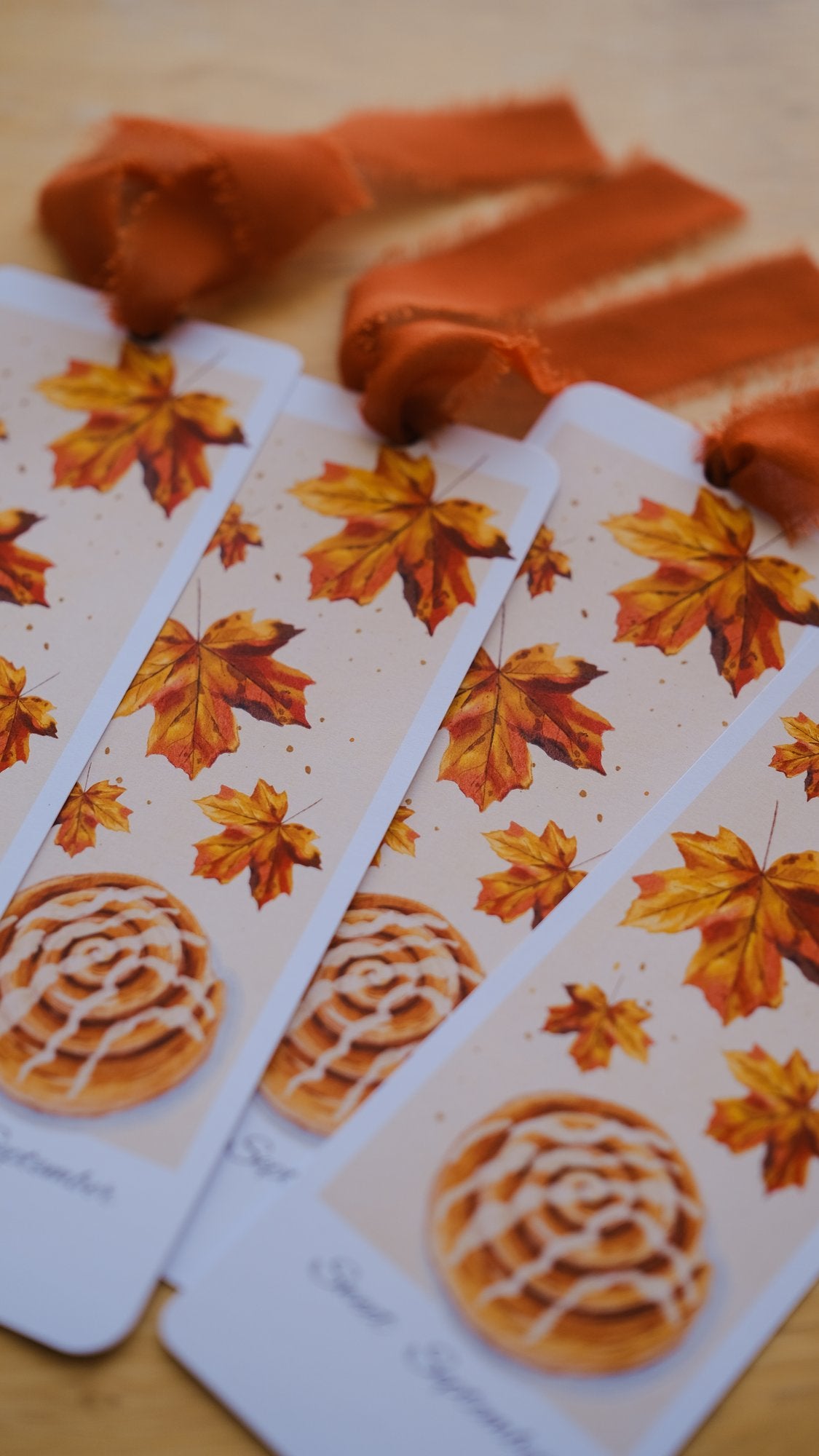 The September 2026 illustrated bookmark with autumn maple leaves and an orange chiffon ribbon, this month's surprise insert.